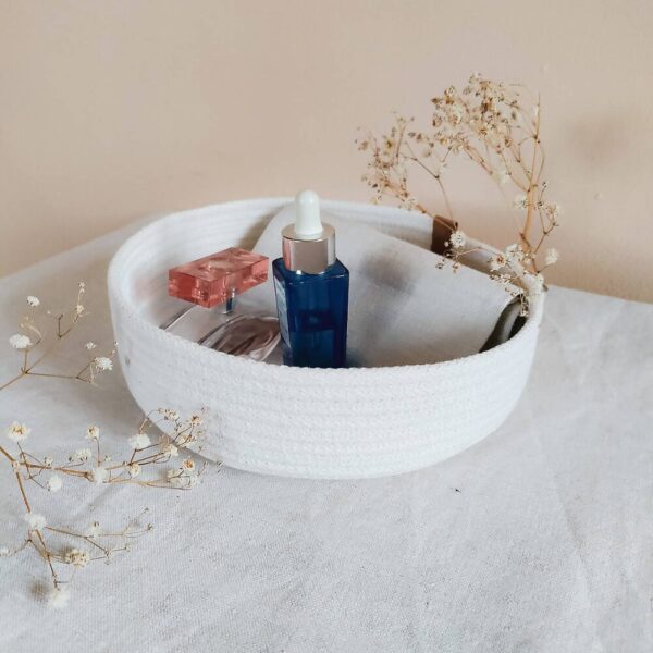 Small cotton rope organizer basket holding perfume and skincare bottles, perfect for desks or vanities.