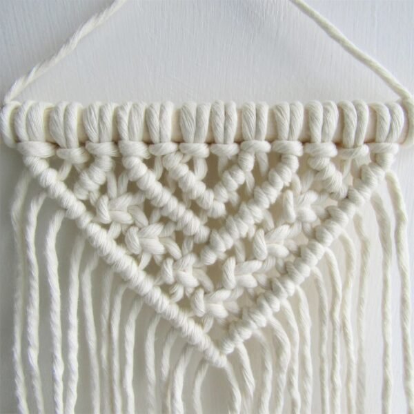 Handmade small macrame wall hanging with V-shaped tassels and wooden rod, perfect for boho home decor.”